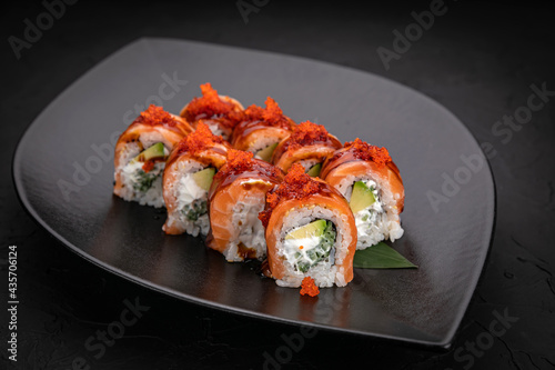 Japanese cuisine. Rolls on a black plate on a wooden table 