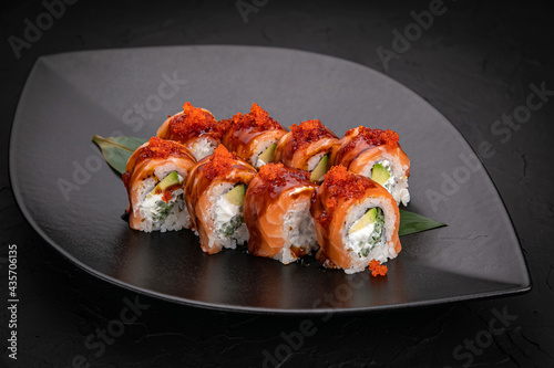 Japanese cuisine. Rolls on a black plate on a wooden table 