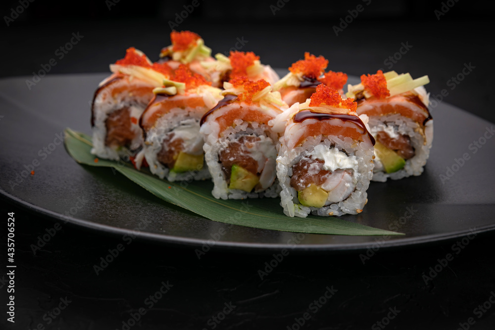 Japanese cuisine. Rolls on a black plate on a wooden table Japanese cuisine. Rolls on a black plate on a wooden table
