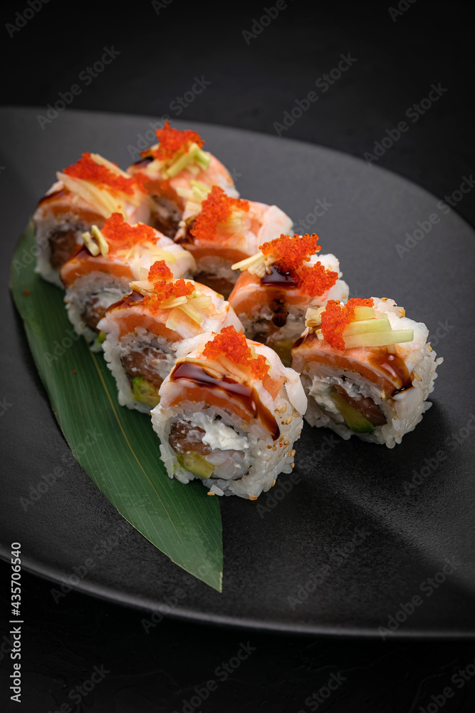 Japanese cuisine. Rolls on a black plate on a wooden table Japanese cuisine. Rolls on a black plate on a wooden table