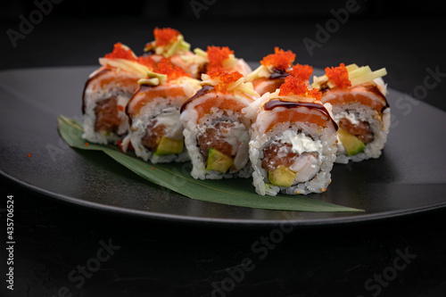 Japanese cuisine. Rolls on a black plate on a wooden table