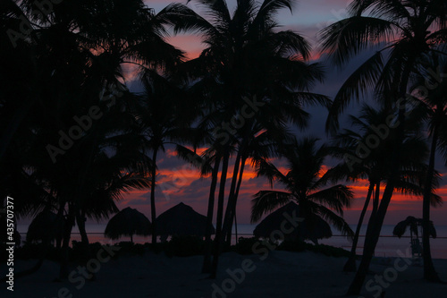 wschód słońca na karaibskiej plaży na Dominikanie w tle z palmami i z chmurami