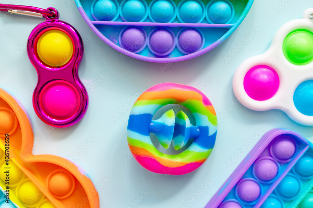 colorful antistress sensory toys fidget push pop it and trendy toy Snapperz on blue background - obrazy, fototapety, plakaty 
