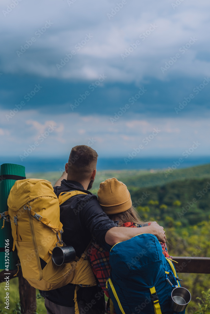 Young couple of hikers hugging while enjoying the view of nature