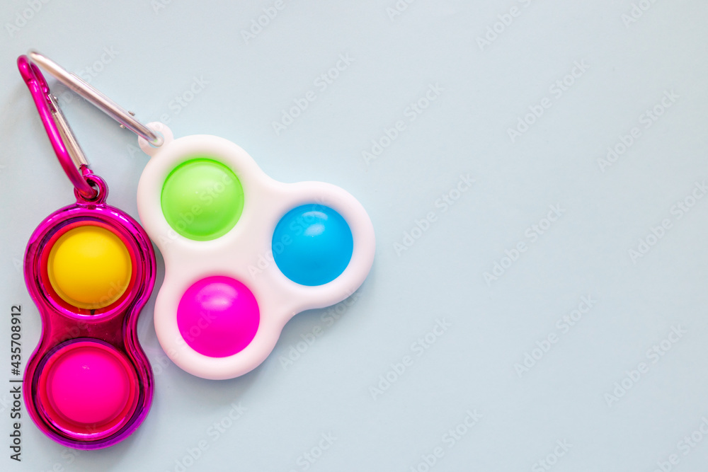 colorful antistress sensory toy fidget push simple dimple on blue background - obrazy, fototapety, plakaty 