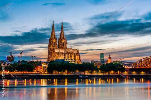 Panoramic view of Cologne Cathedral with Hohenzollern Bridge at nightfall, Germany.
