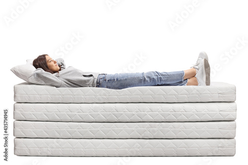 Full length shot of a young female in jeans laying on a pile of mattresses