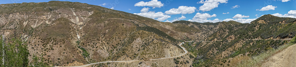 Los Padres National Forest, CA, USA - April 8, 2010: Wide panorama view of brown and green forested mountain flanks and tops with road 33 meandering in western part of park.