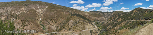Los Padres National Forest, CA, USA - April 8, 2010: Wide panorama view of brown and green forested mountain flanks and tops with road 33 meandering in western part of park.