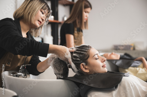 professional hairdresser working to water washing hair clean with woman client in beauty salon, coiffure, female head treatment with shampoo hair care, girl coiffure fashion concept