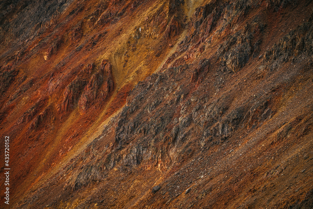 Scenic nature background of multicolor mountain. Colorful nature backdrop of motley rocks. Multicolor great rocks of vivid colors. Beautiful red orange rufous golden rocks. Closeup of motley mountain.