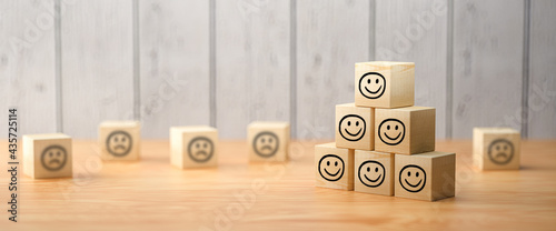 stacked cubes with smiley symbols in front of a wooden background