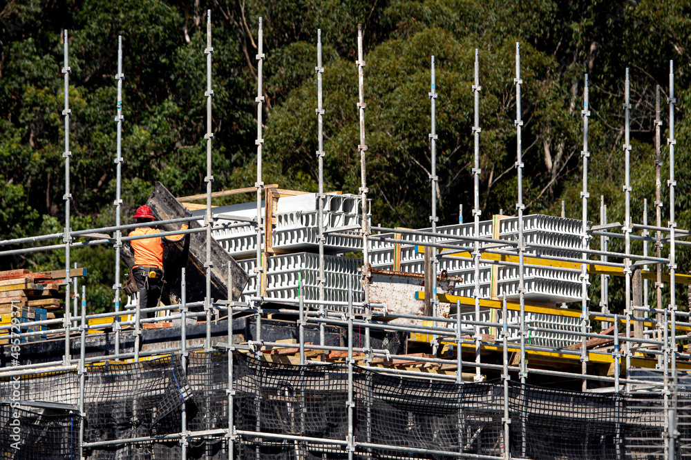 Worker assembling ply floor formwork and PVC concrete wall formwork on the top floor of new unit block at 56-58 Beane St. Gosford, Australia. April 10, 2021. Part of a series.