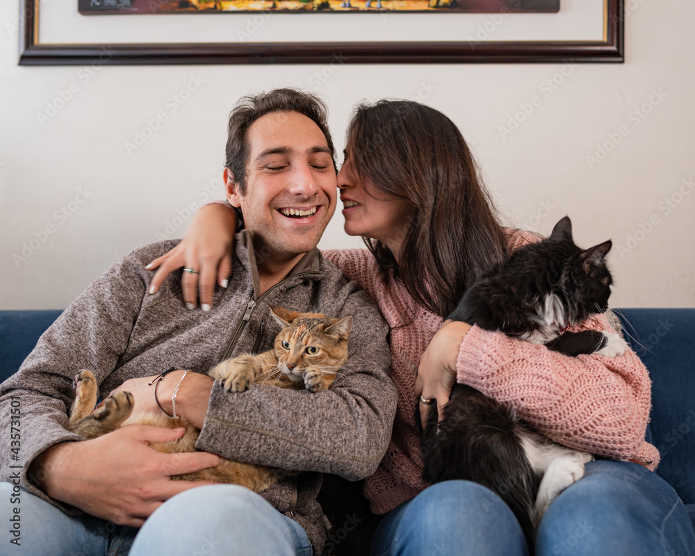 Beautiful couple having a good time with their cats at the living room Beautiful couple having a good time with their cats at the living room