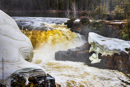 Image of Pisew Falls on the Grass River in Northern Manitoba, Canada, showing water falls as well as remaining snow and ice on the river bank from winter. photo