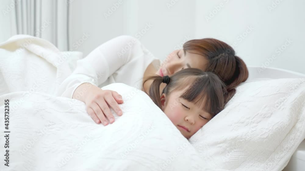 ベッドに横たわる娘を見守る母 ベッドに横たわる娘を見守る母
