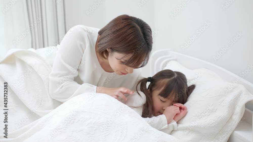 ベッドに横たわる娘を見守る母 ベッドに横たわる娘を見守る母