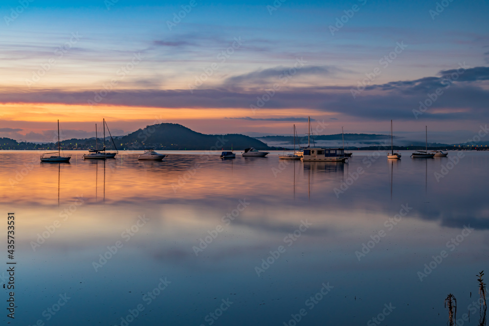 Dawn waterscape with boats, light cloud and fog