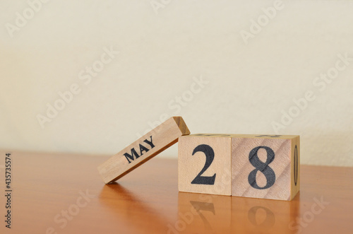 May 28, Date design with calendar cube on wooden table and white background.