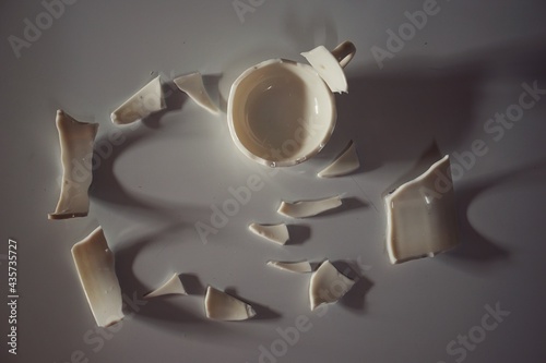 Obraz na płótnie A broken white glass cup crumbled on the floor