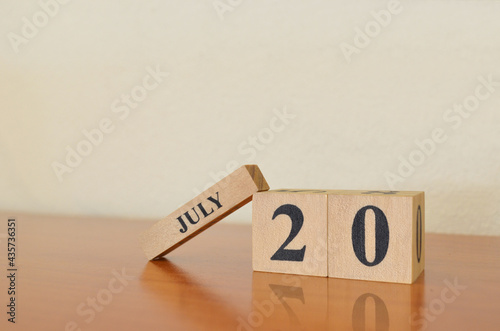 July 20, Date design with calendar cube on wooden table and white background.
