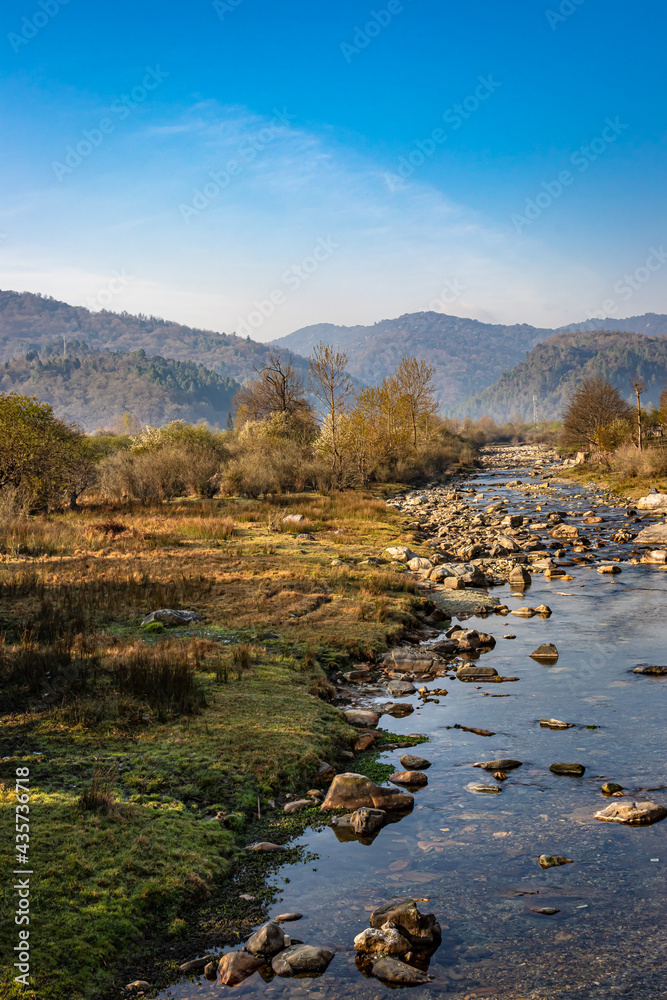 river flowing through misty mountain valley covered with dense forests and blue sky at dawn river flowing through misty mountain valley covered with dense forests and blue sky at dawn