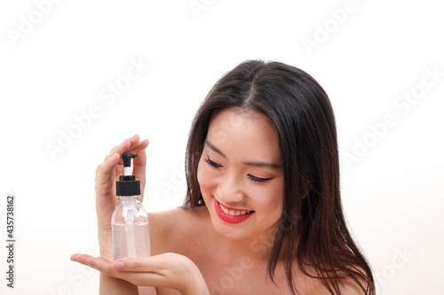 Beautiful young south east Asian woman posing holding using squeeze transparent liquid hand sanitizer plastic bottle pose see offer white background