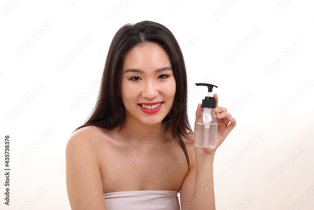 Beautiful young south east Asian woman posing holding transparent liquid hand sanitizer plastic bottle pose see offer white background smile
