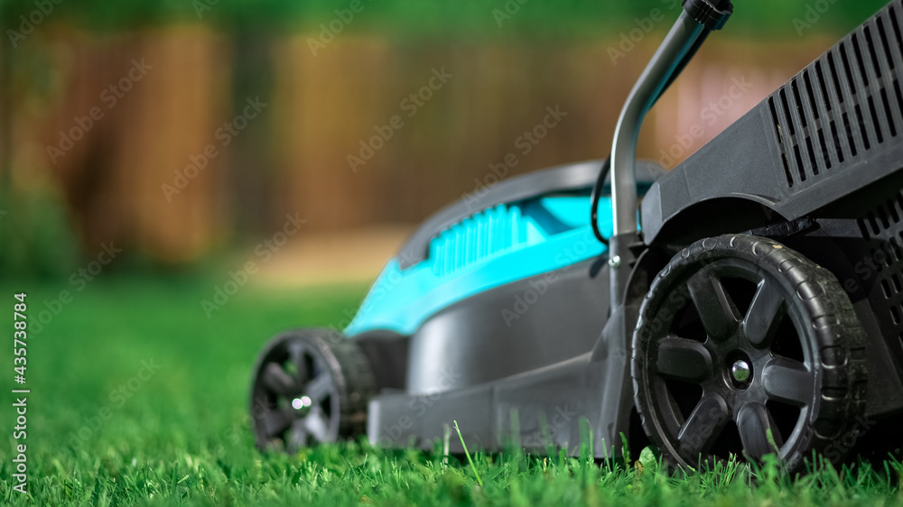 Lawn grass mowing. Worker cutting grass in a green yard. A man with an electric lawn mower mowing a lawn. Gardener pruning a garden Lawn grass mowing. Worker cutting grass in a green yard. A man with an electric lawn mower mowing a lawn. Gardener pruning a garden