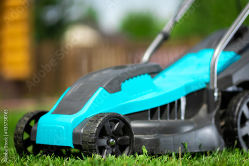 Close up of the  electric lawn mower mowing the lawn. Pruning and landscaping a garden, cutting grass, lawn, paths