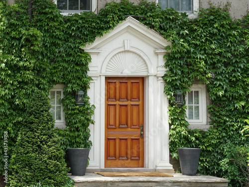 Elegant wood grain front door of ivy covered house