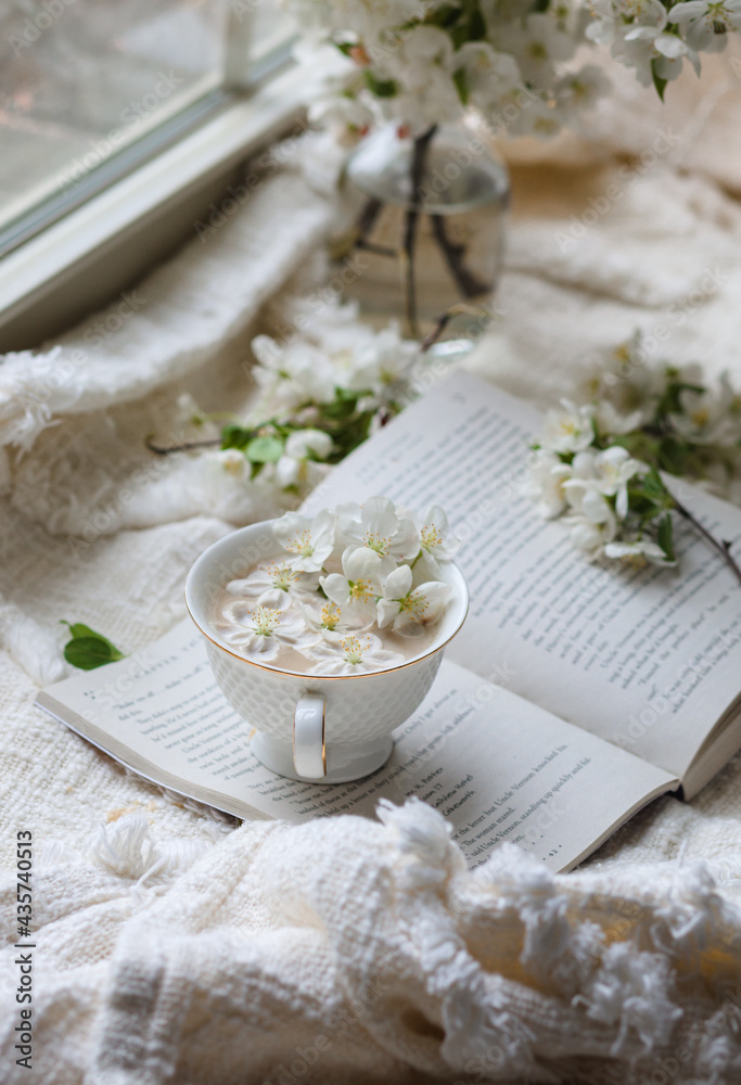 Fresh Spring blossom with a cup of coffee near window with raindrops where sheer curtain and string lights are hanging Fresh Spring blossom with a cup of coffee near window with raindrops where sheer curtain and string lights are hanging