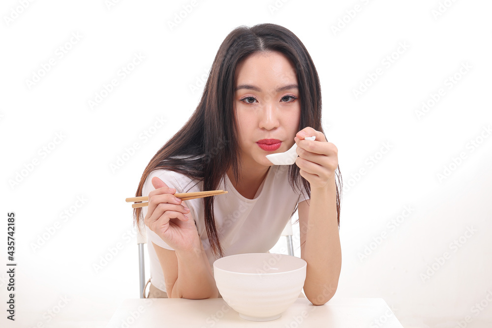 Beautiful young south east Asian woman holding chinese empty chopstick soup spoon bowl utensil pretend acting posing see eat taste feed offer satisfaction yummy white background happy Beautiful young south east Asian woman holding chinese empty chopstick soup spoon bowl utensil pretend acting posing see eat taste feed offer satisfaction yummy white background happy