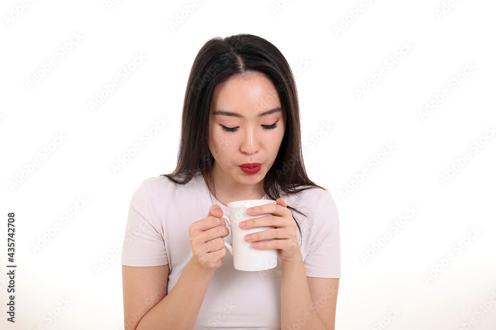 Beautiful young south east Asian woman holding white coffee tea cup emotion expression on white background look down blowing to coo Beautiful young south east Asian woman holding white coffee tea cup emotion expression on white background look down blowing to coo