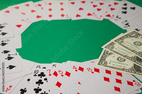 Classic playing cards and dollars on green background. Gambling and casino concept.