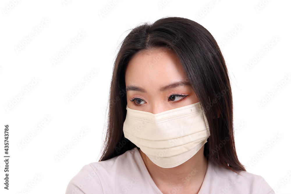 Beautiful young south east Asian woman wearing yellow off white three ply anti virus surgical face mask on white background look right Beautiful young south east Asian woman wearing yellow off white three ply anti virus surgical face mask on white background look right