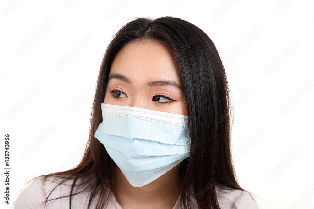 Beautiful young south east Asian woman wearing blue three ply anti virus surgical face mask on white background look right Beautiful young south east Asian woman wearing blue three ply anti virus surgical face mask on white background look right