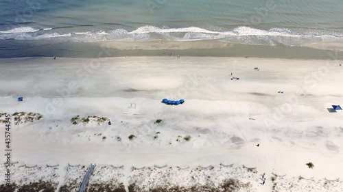 4K Aerial drone shot of Beach coastline with the blue Ocean with waves coming in and beach with nice houses on the background. American suburb. Bright sun enlightens the gorgeous tropical nature photo