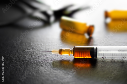 Ketamine in Syringe with blur image of glass bottle and rubber on dark black wooden. dope, opiate, Addictive substance, habit-forming substance, narcotic concept.