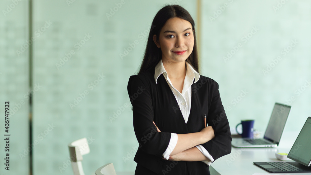 Half-length portrait of businesswoman in formal suit arms crossed and smiling to camera Half-length portrait of businesswoman in formal suit arms crossed and smiling to camera