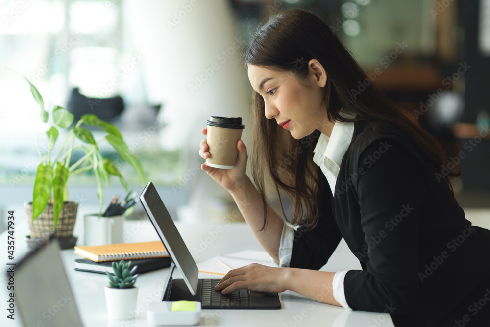 Side view of businesswoman holding paper cup and working with digital tablet Side view of businesswoman holding paper cup and working with digital tablet