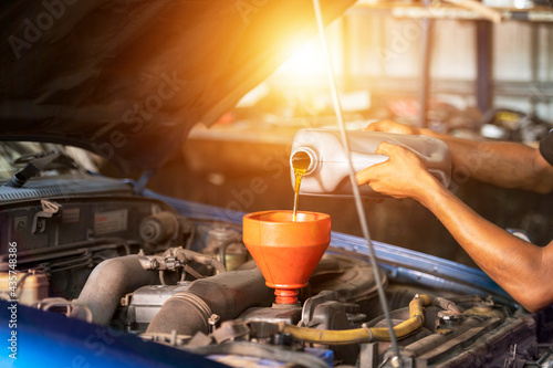 Old car oil change mechanic. Add new oil to the car. Pour fresh oil at the service station. photo