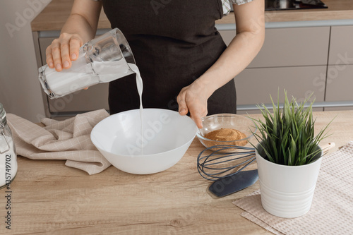 The process of making gluten-free baked goods. Pouring coconut milk into a bowl. The concept of cooking vegetarian pastries.