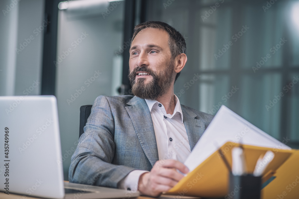 Joyful adult man with folder at table Joyful adult man with folder at table