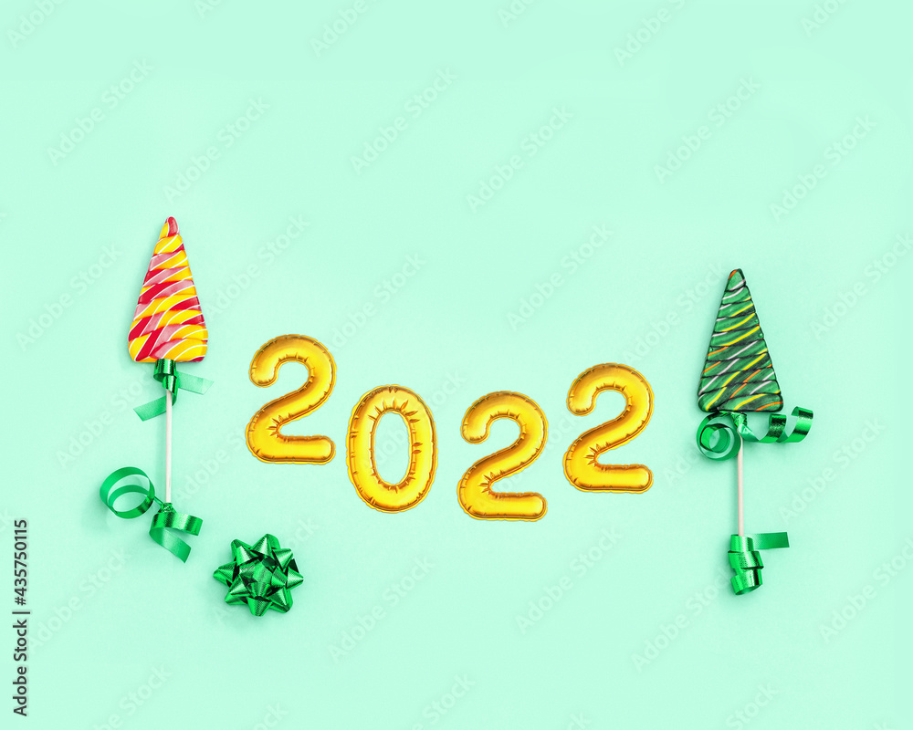 Obraz premium New year background with Lollipops as Christmas tree and metallic gold numeral 2022.