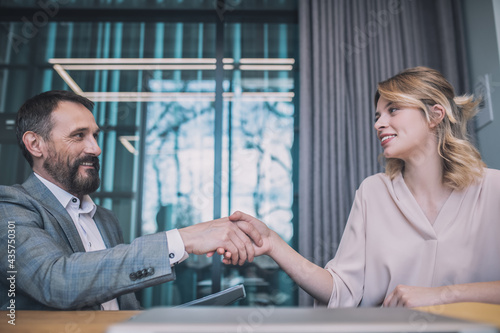 Smiling business man and woman sitting with handshake photo
