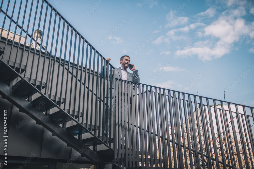 Confident business man talking on smartphone on stairs