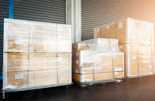 Stacked of Package Boxes Wrapped Plastic Flim on Plastic Pallets at Storage Warehouse. Shipment Boxes. Cargo Export- Import. Shipping Warehouse Logistics.	