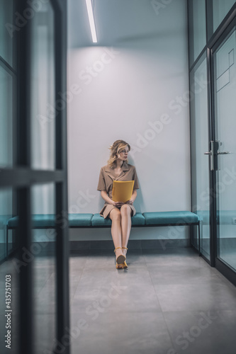 Young blonde woman waiting in the office corridor