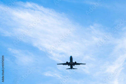 A passenger plane lands on a blue sky background on a warm summer day